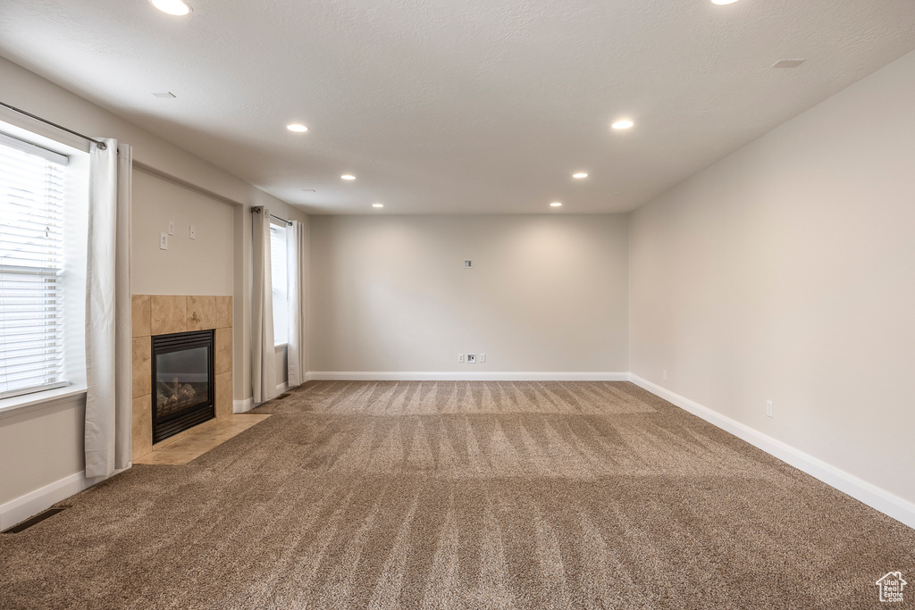 Unfurnished living room with light carpet, a tiled fireplace, visible vents, and recessed lighting