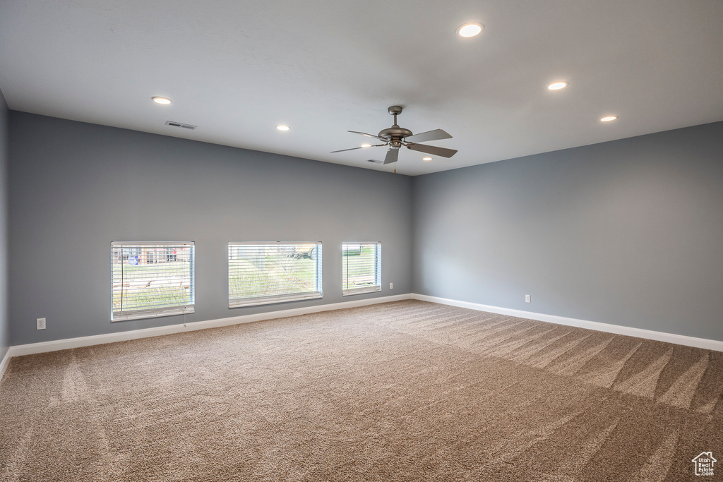 Unfurnished room with carpet flooring, visible vents, baseboards, and ceiling fan