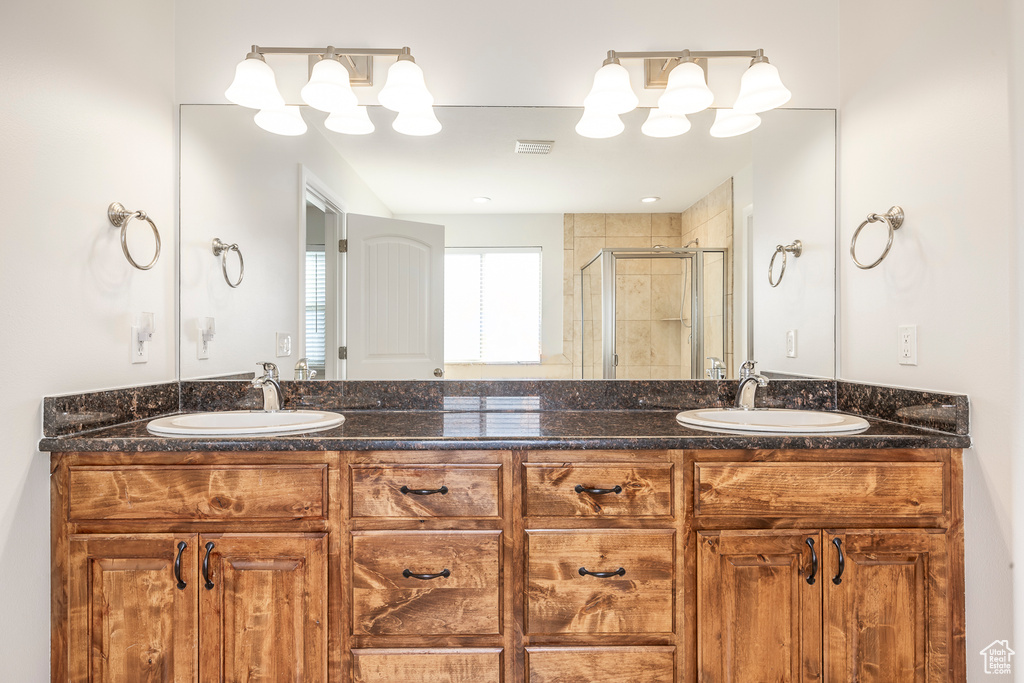 Full bathroom featuring a shower stall, double vanity, and a sink