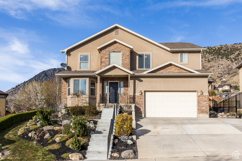 View of front of property featuring driveway, stucco siding, and stone siding