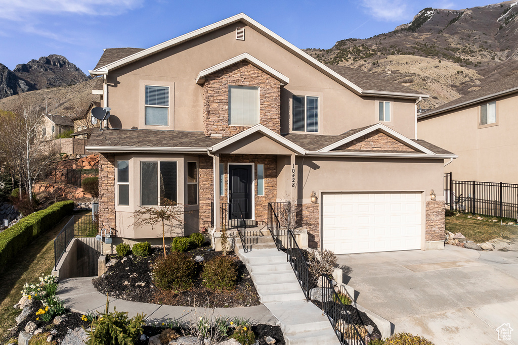 View of front of home with driveway, fence, and stone siding