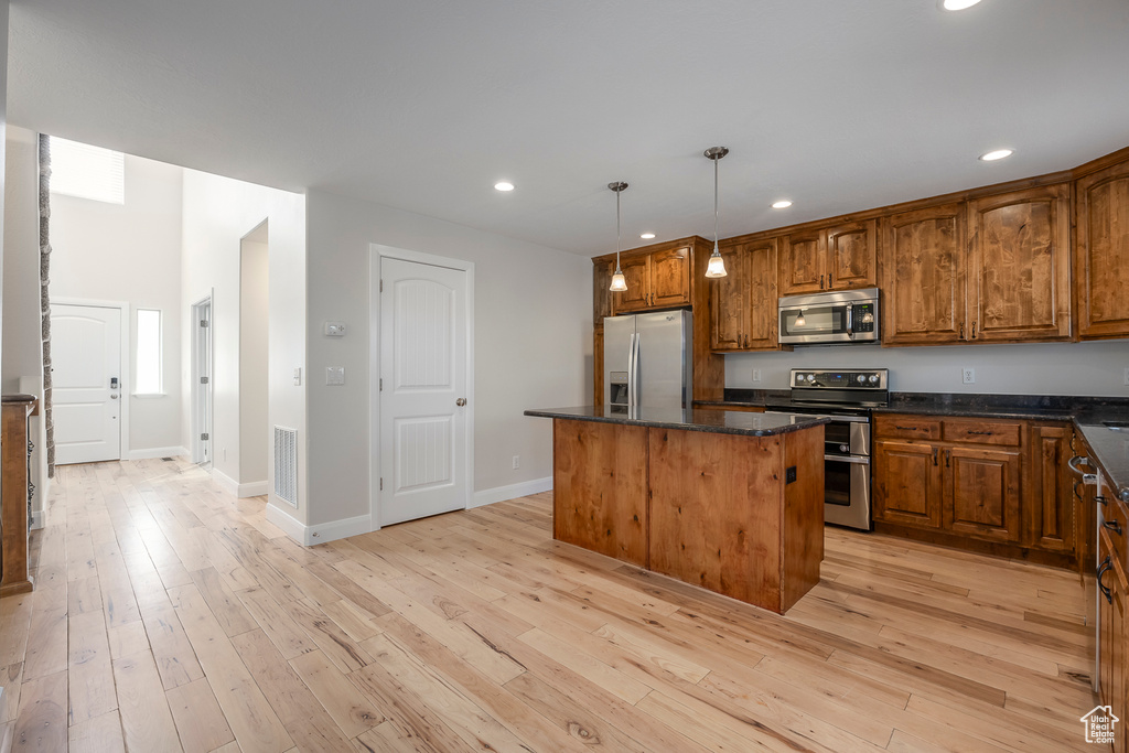 Kitchen featuring light wood-style floors, appliances with stainless steel finishes, visible vents, and a kitchen island