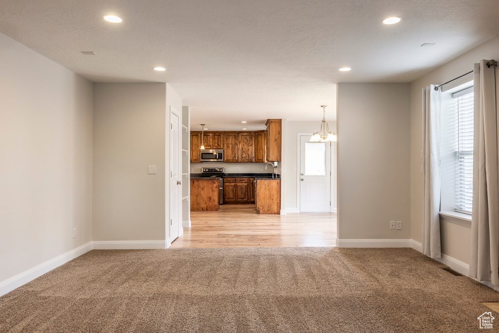 Unfurnished living room with light carpet, recessed lighting, baseboards, and a sink