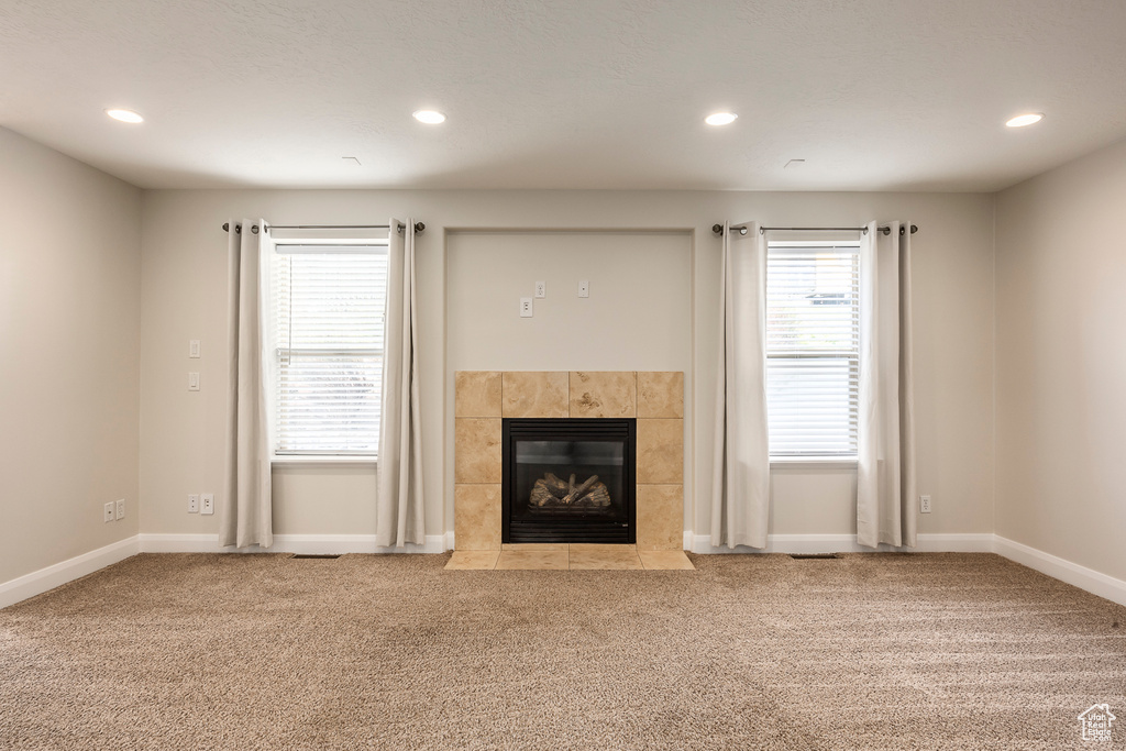 Unfurnished living room featuring a tiled fireplace, carpet, and recessed lighting