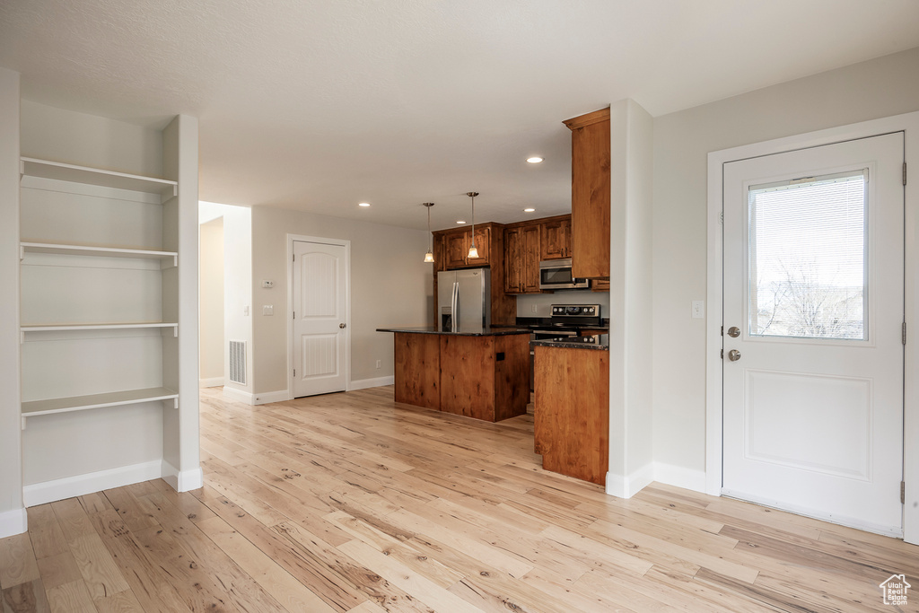 Kitchen featuring light wood-type flooring, visible vents, a kitchen island, dark countertops, and stainless steel appliances