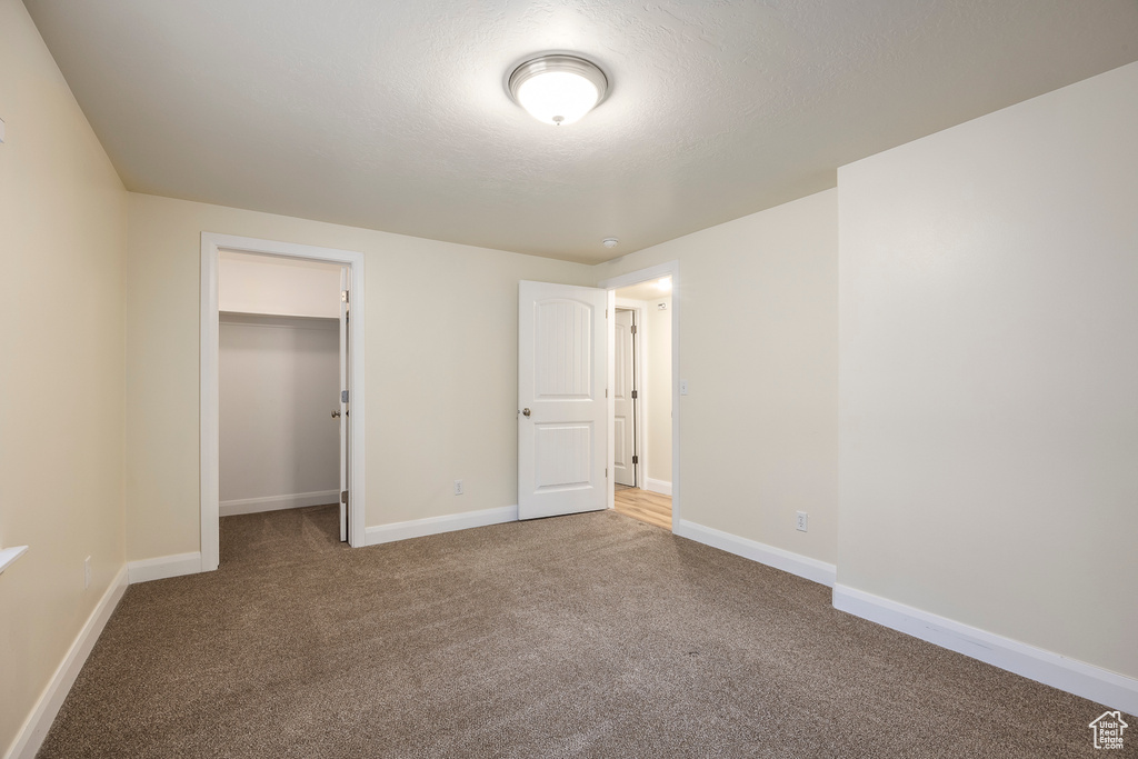 Unfurnished bedroom featuring a closet, baseboards, a spacious closet, and carpet