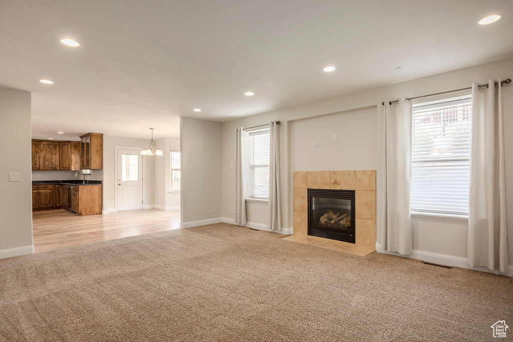 Unfurnished living room featuring visible vents, recessed lighting, a tile fireplace, and light carpet