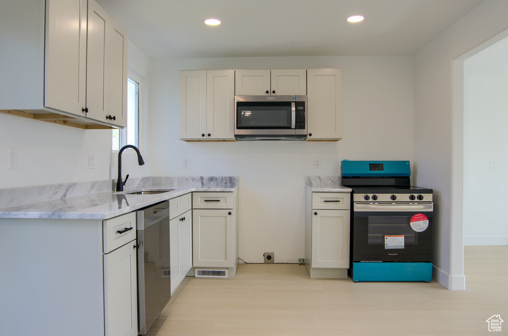 Kitchen with visible vents, a sink, recessed lighting, stainless steel appliances, and light stone counters