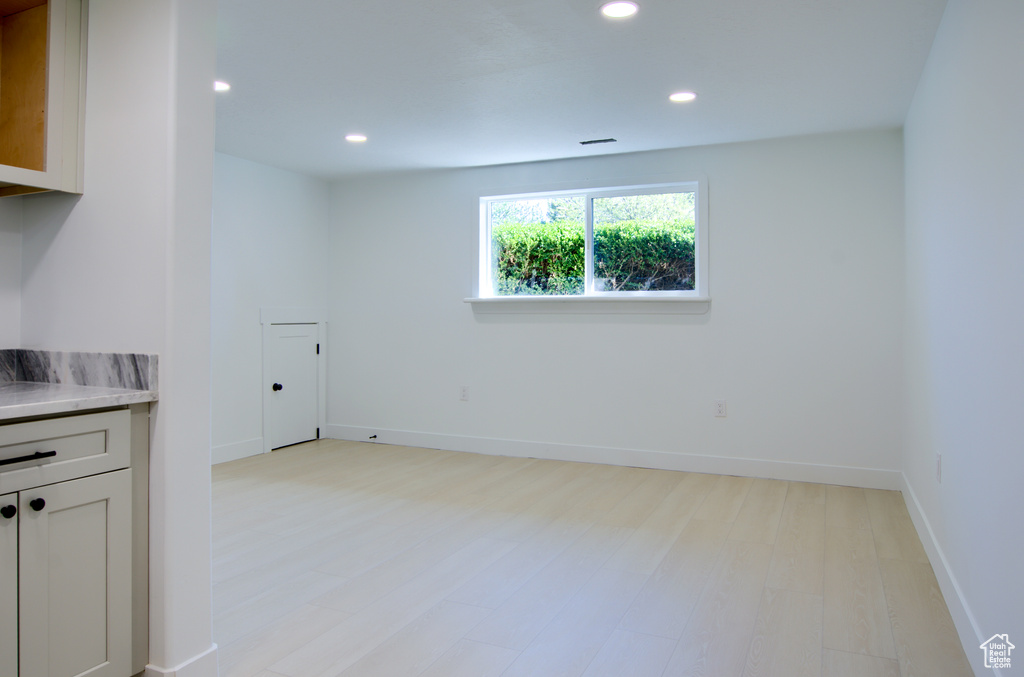 Empty room featuring light wood-style floors, baseboards, and recessed lighting