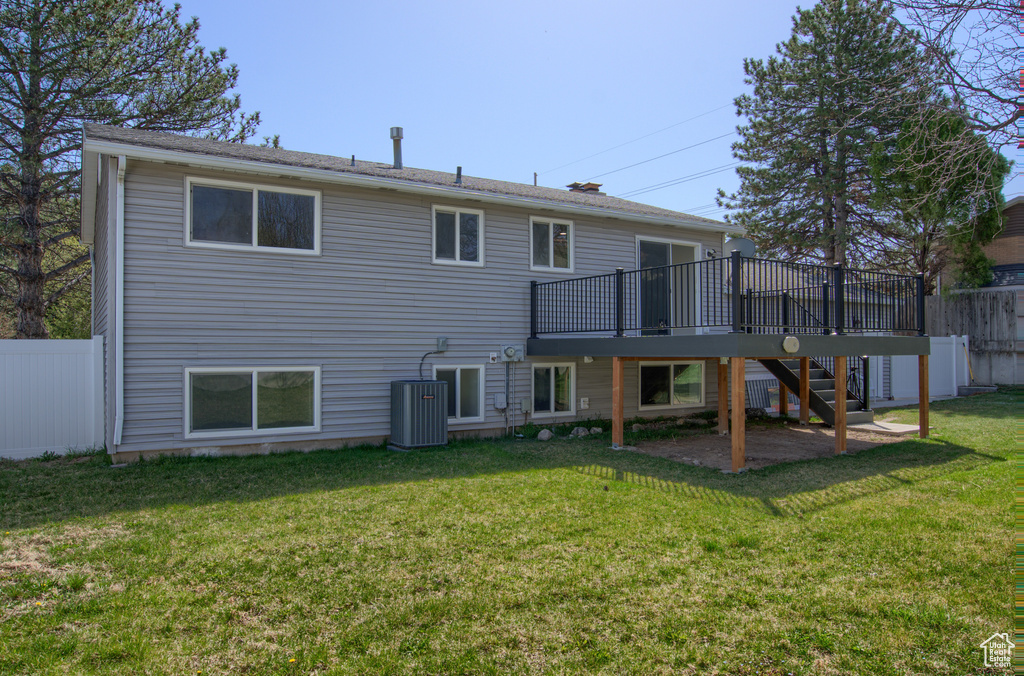 Back of property featuring stairs, central AC unit, a wooden deck, a yard, and fence