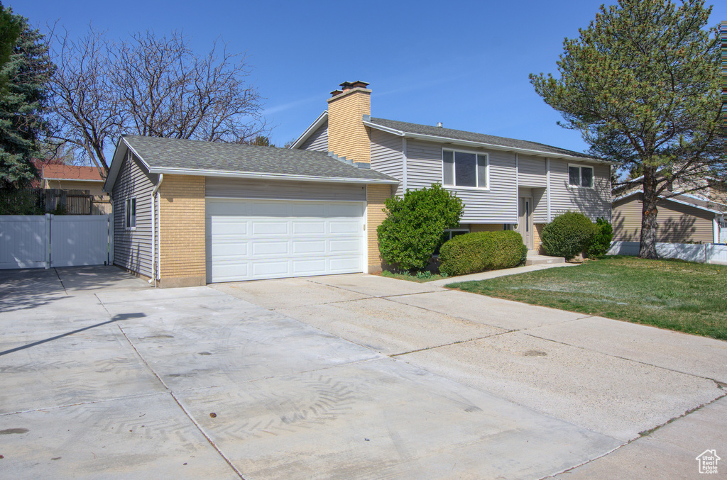 View of front of property with a garage, fence, brick siding, a chimney, and driveway