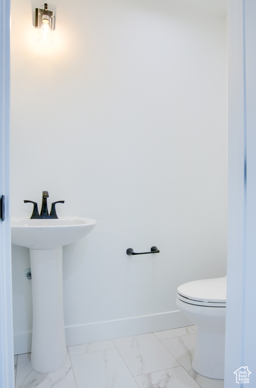 Bathroom featuring toilet, baseboards, and marble finish floor