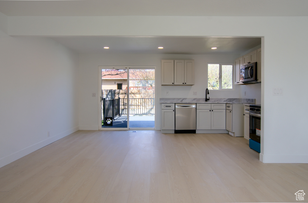 Kitchen with light wood finished floors, baseboards, a sink, and appliances with stainless steel finishes