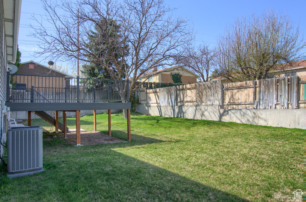 View of yard featuring stairway, central AC, a wooden deck, and fence