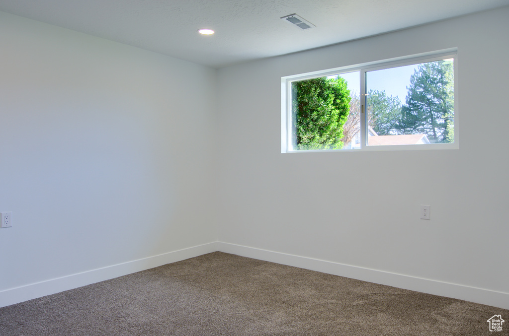 Unfurnished room featuring dark carpet, baseboards, visible vents, and recessed lighting