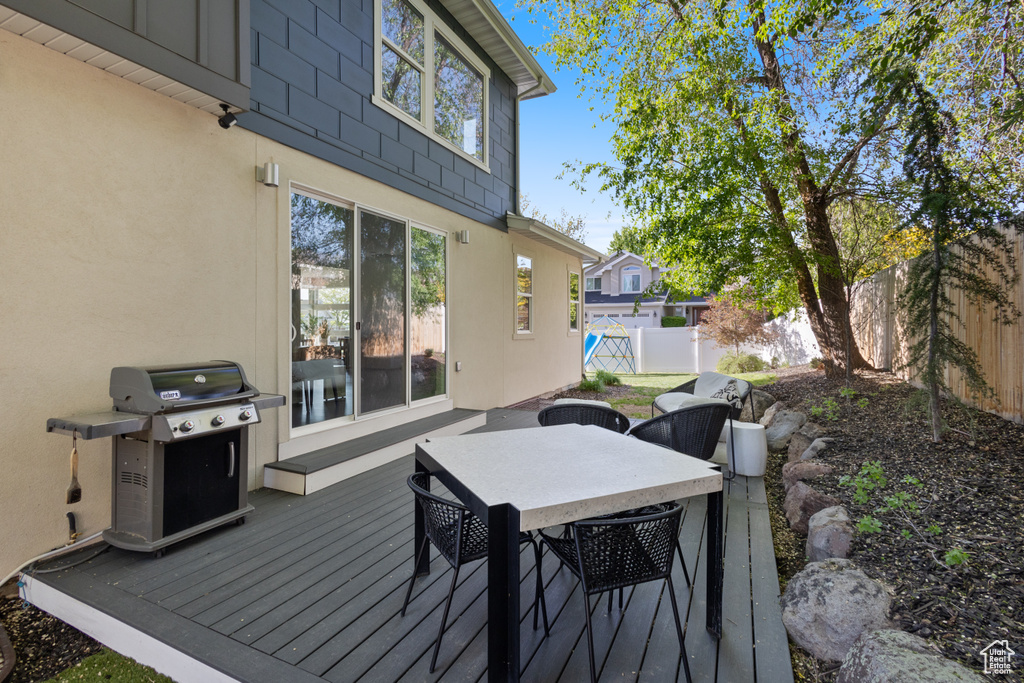 Deck with a grill, a fenced backyard, and outdoor dining space