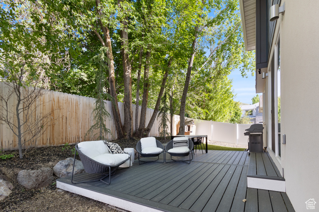 Wooden terrace featuring a fenced backyard and a grill