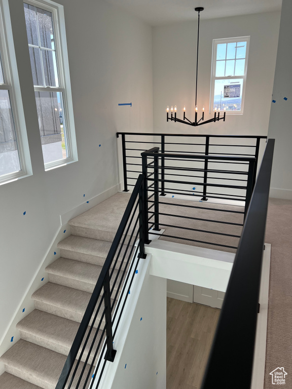 Staircase featuring baseboards, wood finished floors, and a notable chandelier