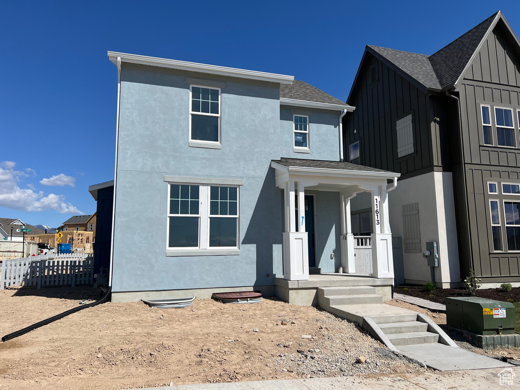 Modern farmhouse style home featuring board and batten siding, fence, a porch, and stucco siding