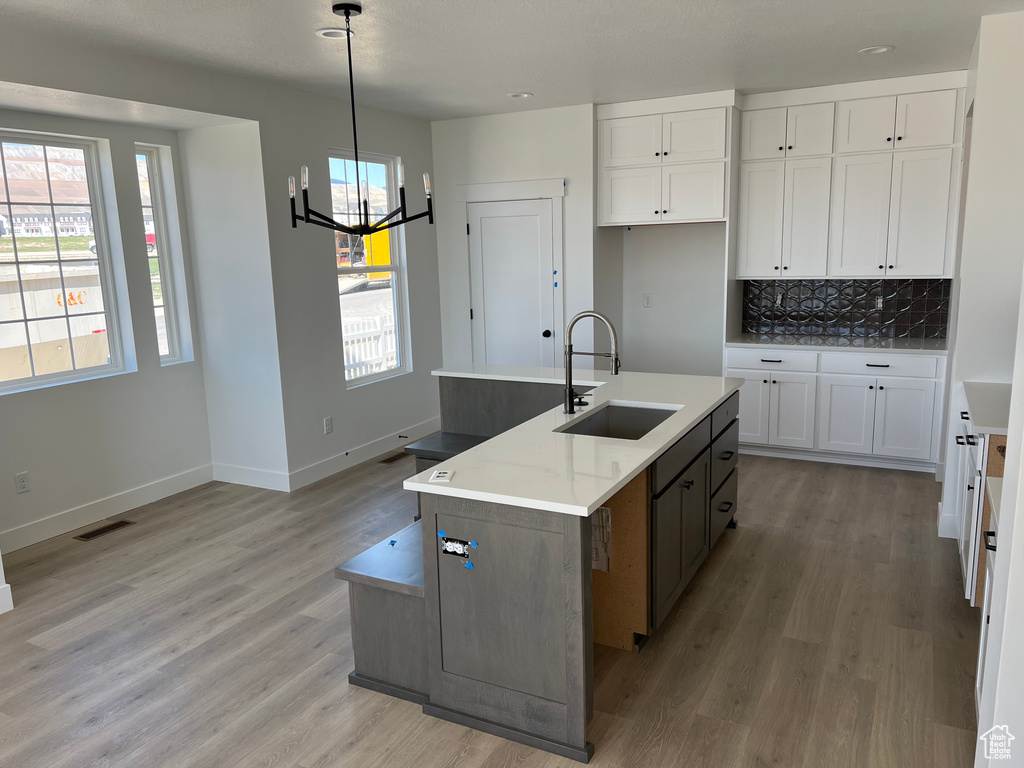 Kitchen with a sink, white cabinetry, and light wood-style flooring