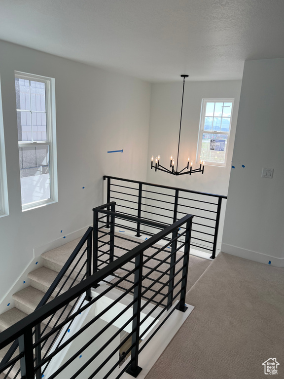 Staircase featuring baseboards, carpet flooring, and a notable chandelier