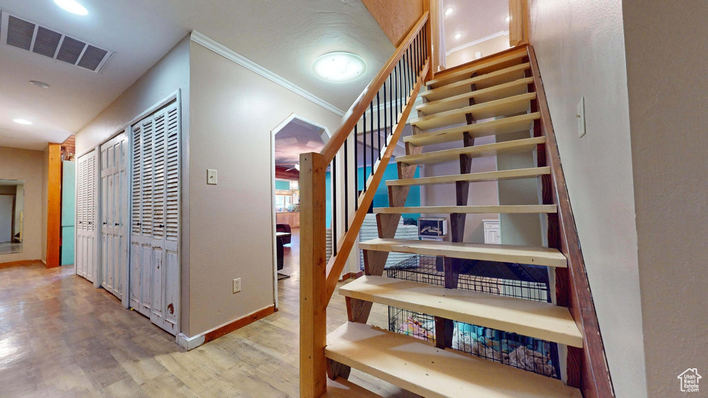 Stairs featuring wood finished floors, recessed lighting, and crown molding