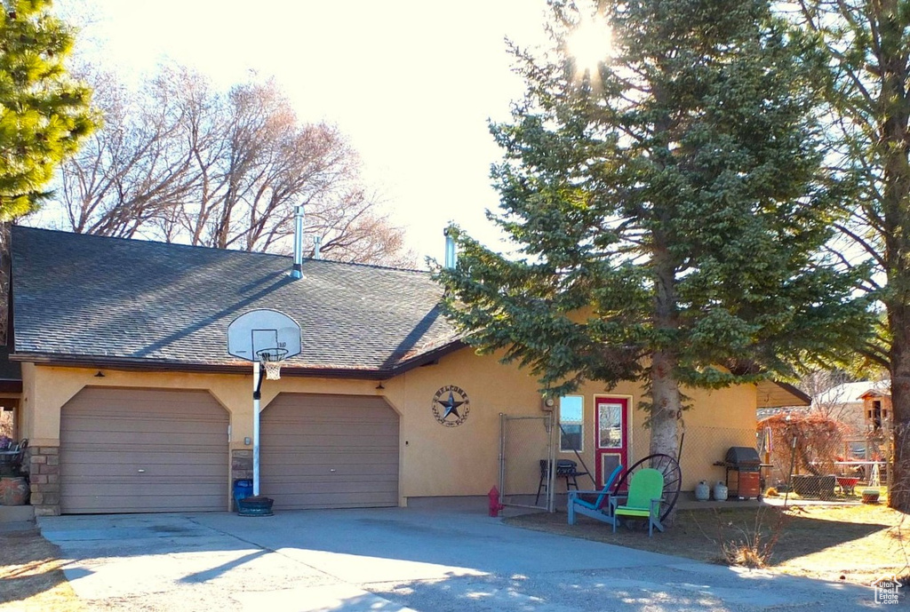 View of front of home featuring stucco siding, an attached garage, a shingled roof, and driveway