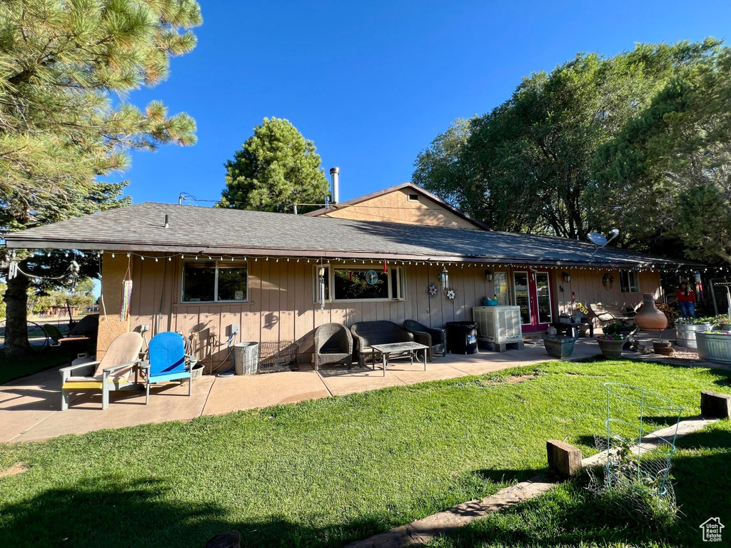 Rear view of property with a patio, a yard, and a shingled roof