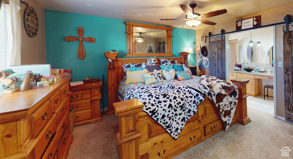 Bedroom featuring a barn door, light colored carpet, and connected bathroom