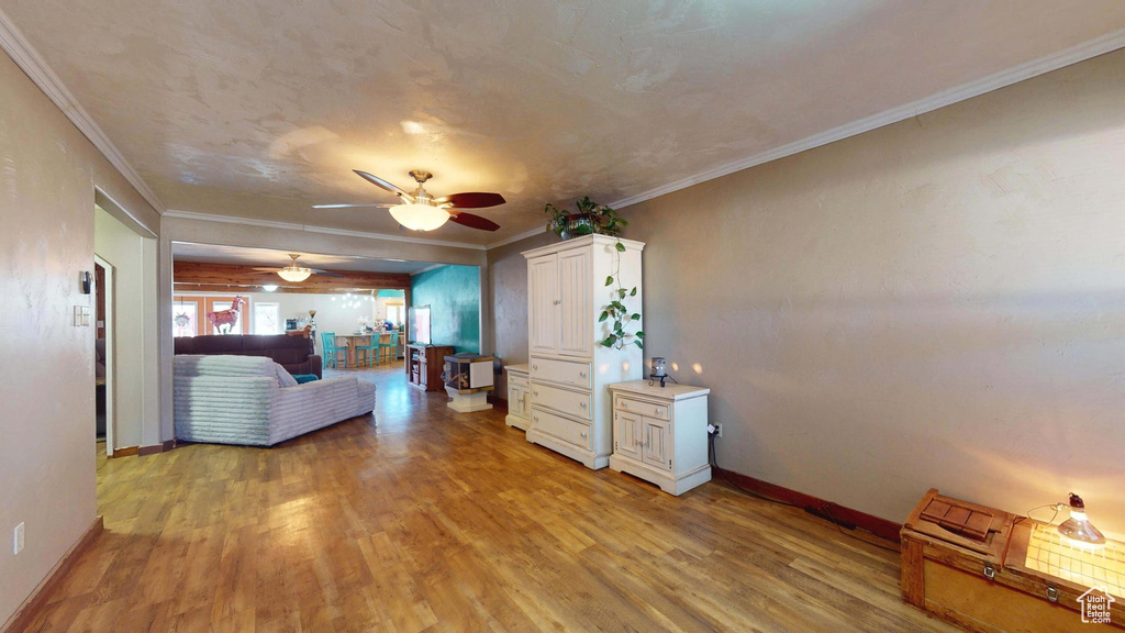 Living area featuring light wood-style flooring, a ceiling fan, and crown molding