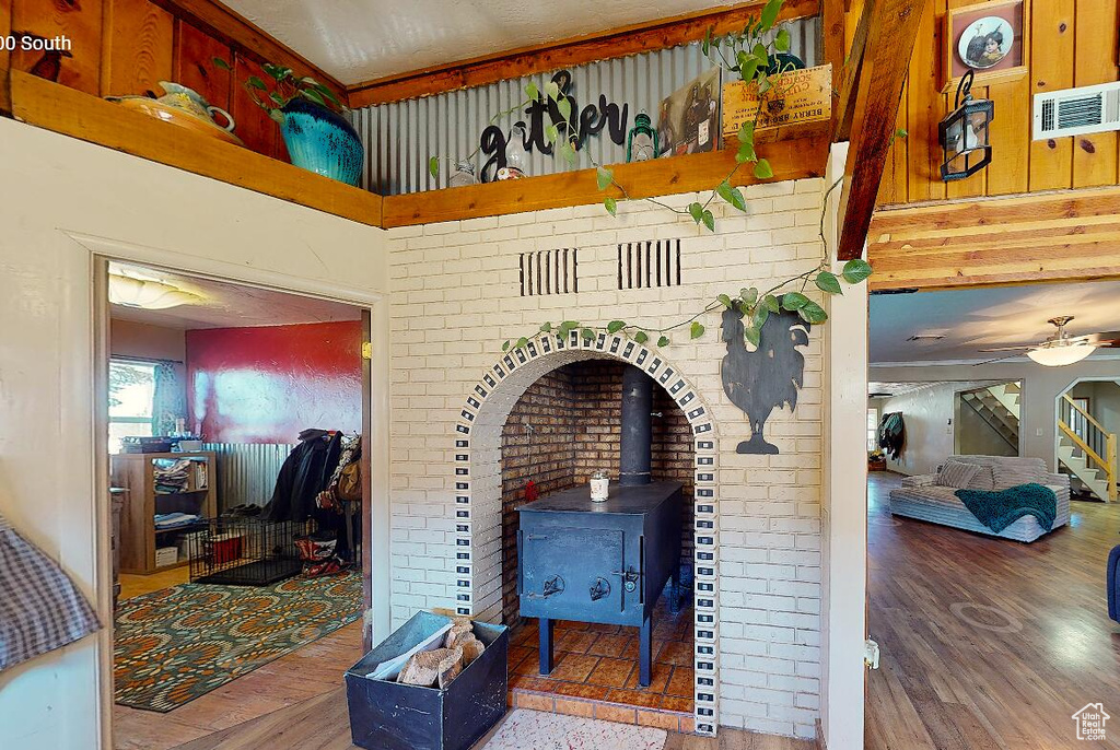 Living room featuring a wood stove, wood finished floors, and ceiling fan