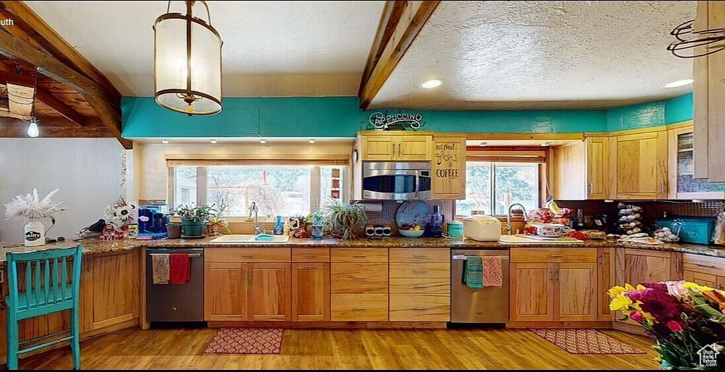 Kitchen featuring stainless steel appliances, light wood-style flooring, dark stone countertops, and recessed lighting