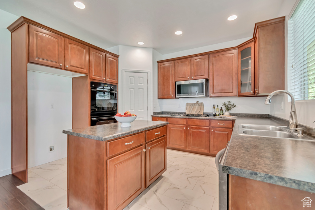 Kitchen featuring a sink, stainless steel microwave, light marble finish floors, glass insert cabinets, and recessed lighting