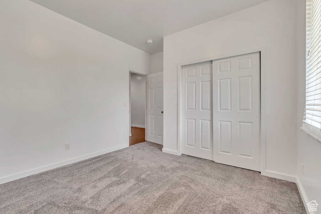 Unfurnished bedroom featuring carpet floors, baseboards, and a closet