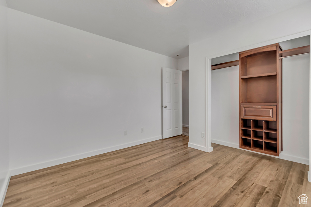 Unfurnished bedroom featuring light wood-style floors, baseboards, and a closet