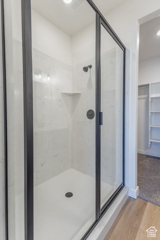 Bathroom featuring a stall shower, wood finished floors, and a spacious closet