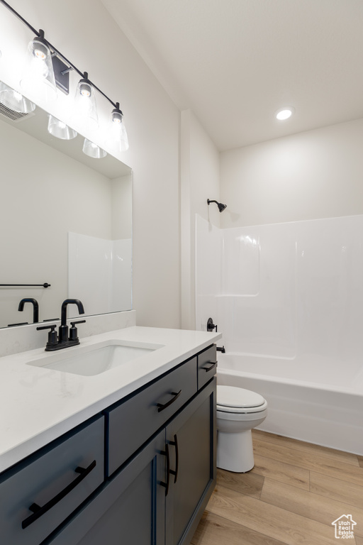 Bathroom with toilet, recessed lighting, wood finished floors, vanity, and tub / shower combination