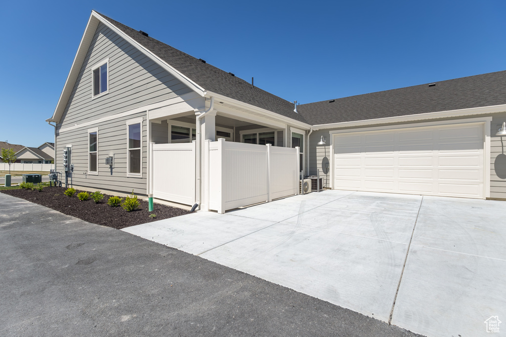 View of front of property with driveway, a garage, roof with shingles, and fence