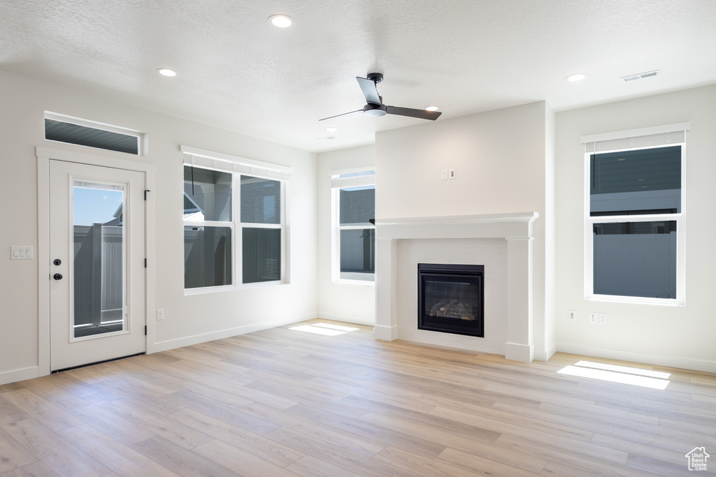 Unfurnished living room featuring a ceiling fan, wood finished floors, a glass covered fireplace, baseboards, and recessed lighting