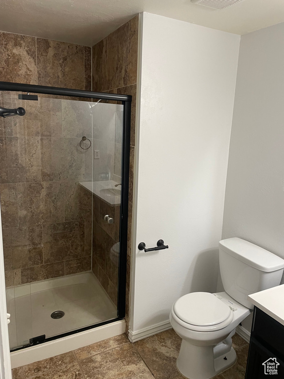 Full bathroom featuring visible vents, baseboards, toilet, a shower stall, and vanity
