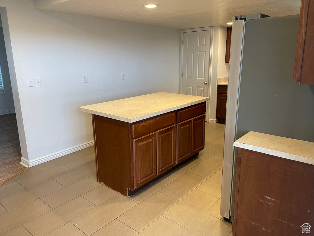 Kitchen with baseboards, light countertops, freestanding refrigerator, and wood tiled floor