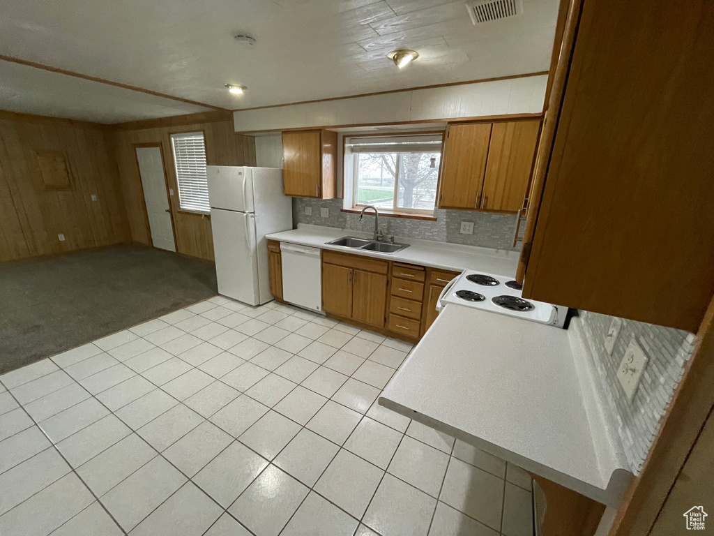 Kitchen featuring white appliances, wooden walls, light countertops, visible vents, and a sink