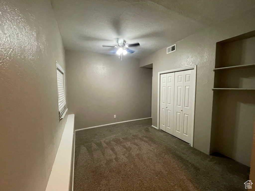 Unfurnished bedroom with a closet, a textured wall, carpet flooring, a textured ceiling, and visible vents