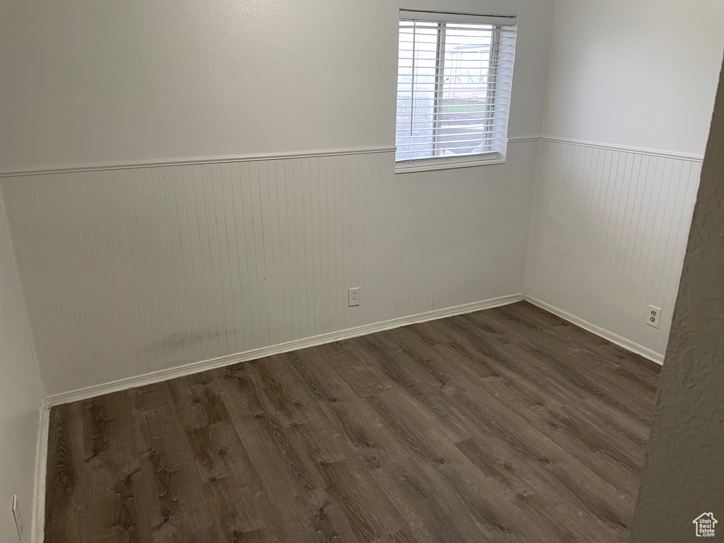 Unfurnished room with dark wood finished floors and a wainscoted wall