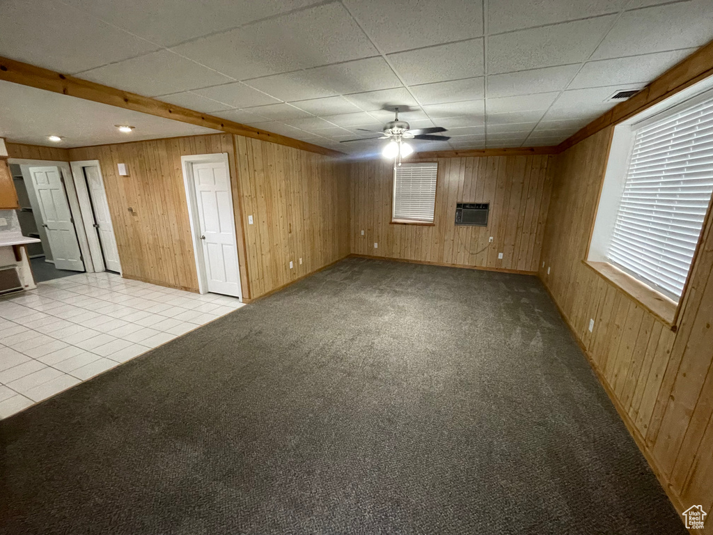 Unfurnished living room featuring visible vents, wood walls, a drop ceiling, and light carpet