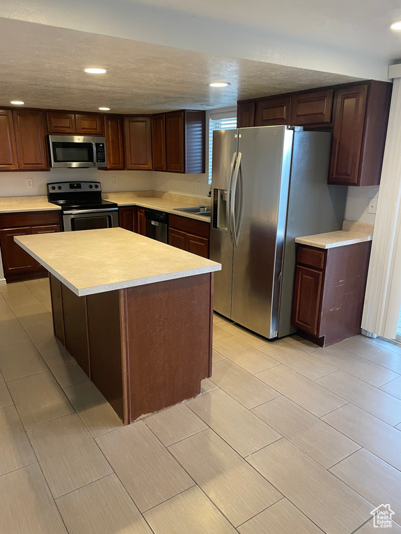 Kitchen with a center island, a sink, light countertops, recessed lighting, and stainless steel appliances