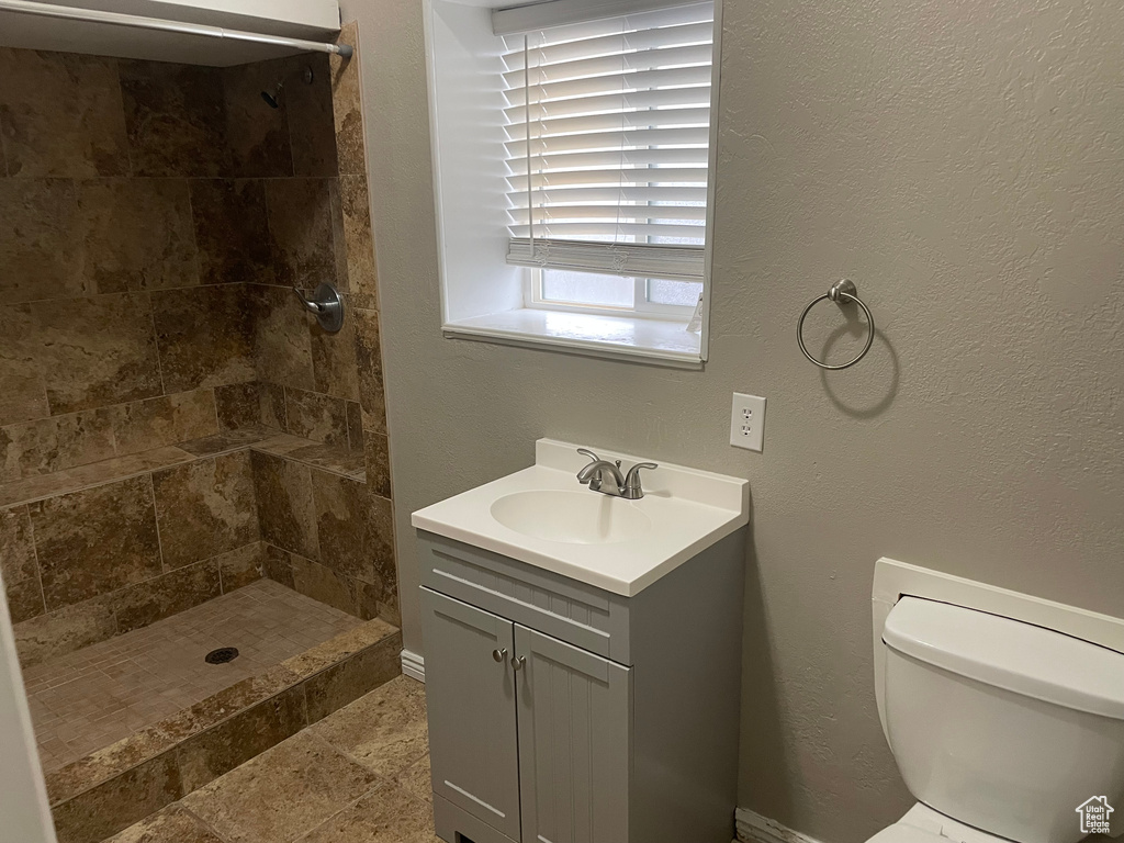 Bathroom with toilet, tiled shower, and vanity