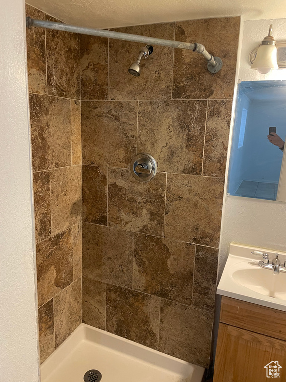 Bathroom with a textured ceiling, a stall shower, and vanity