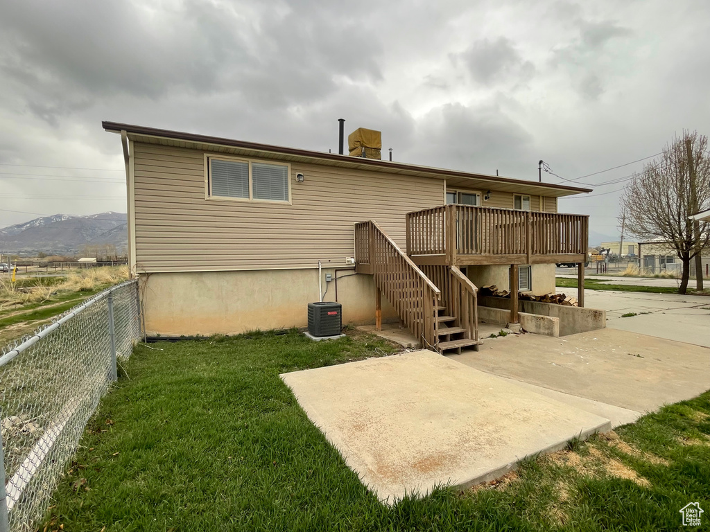 Rear view of house featuring a deck, a patio area, a lawn, fence, and stairway