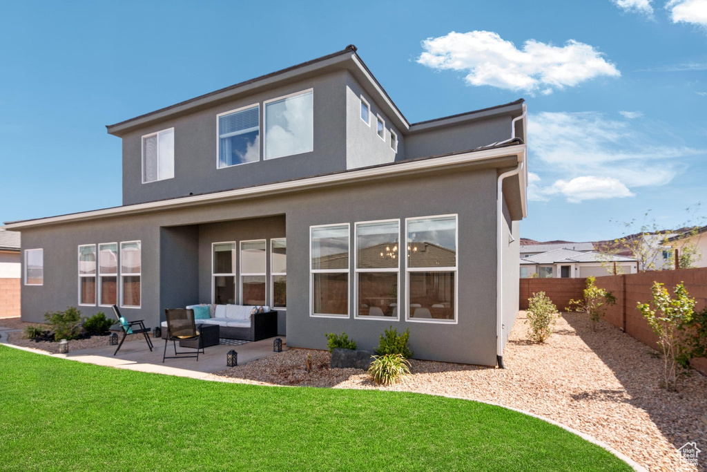 Rear view of house featuring stucco siding, a patio, a fenced backyard, outdoor lounge area, and a lawn